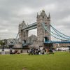 Iconic Tower Bridge in London with people enjoying a park view on a cloudy day.